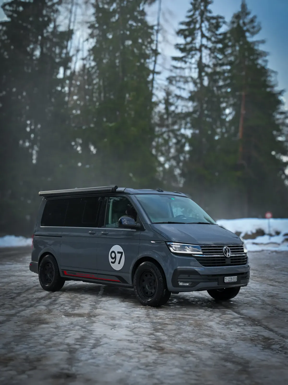 Il VW California di Garage Novantasette con il 97 sulla portiera, nel bosco innevato